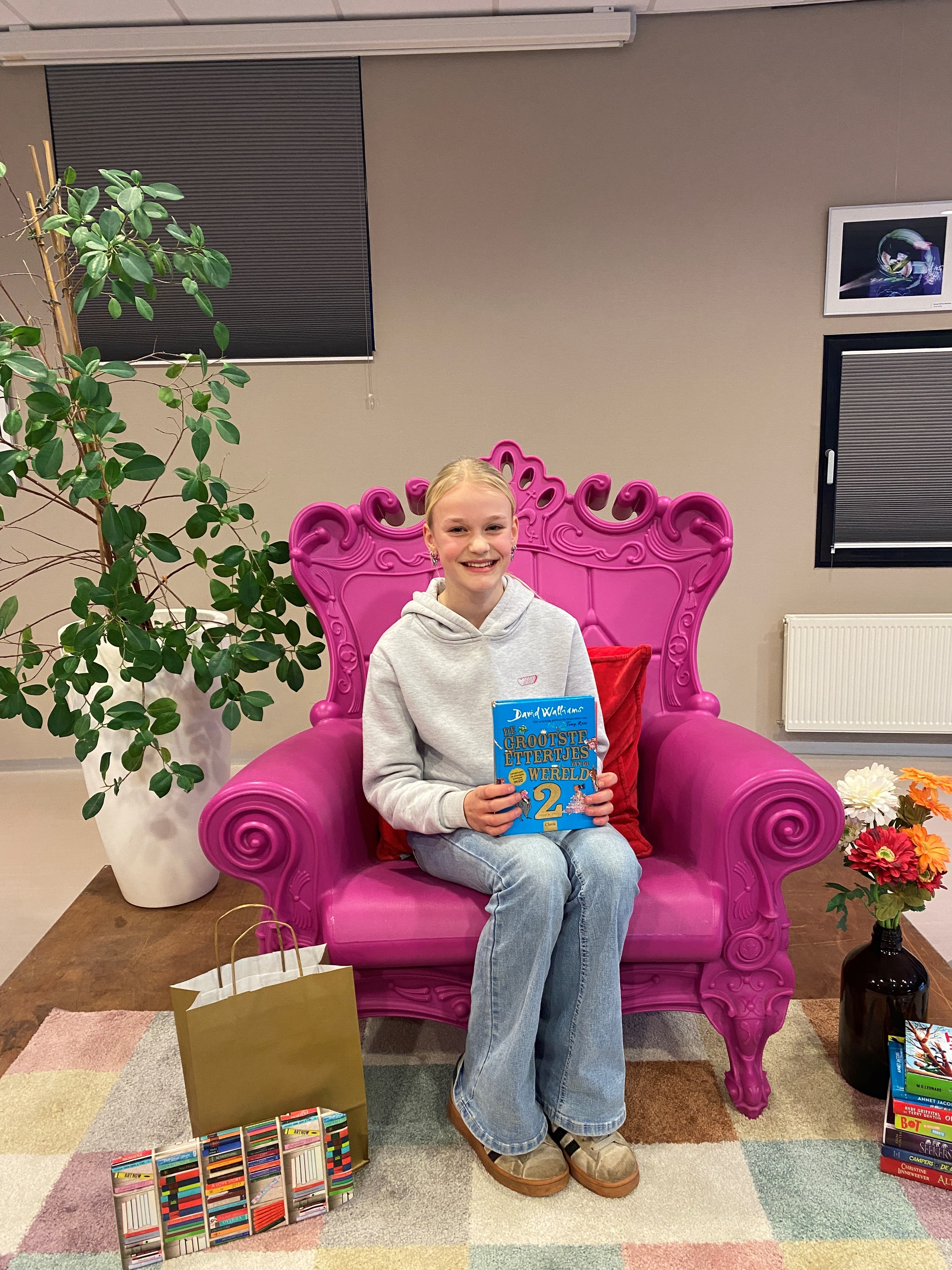 Esmée Harmsen zit op een grote, roze stoel met een boek in haar handen