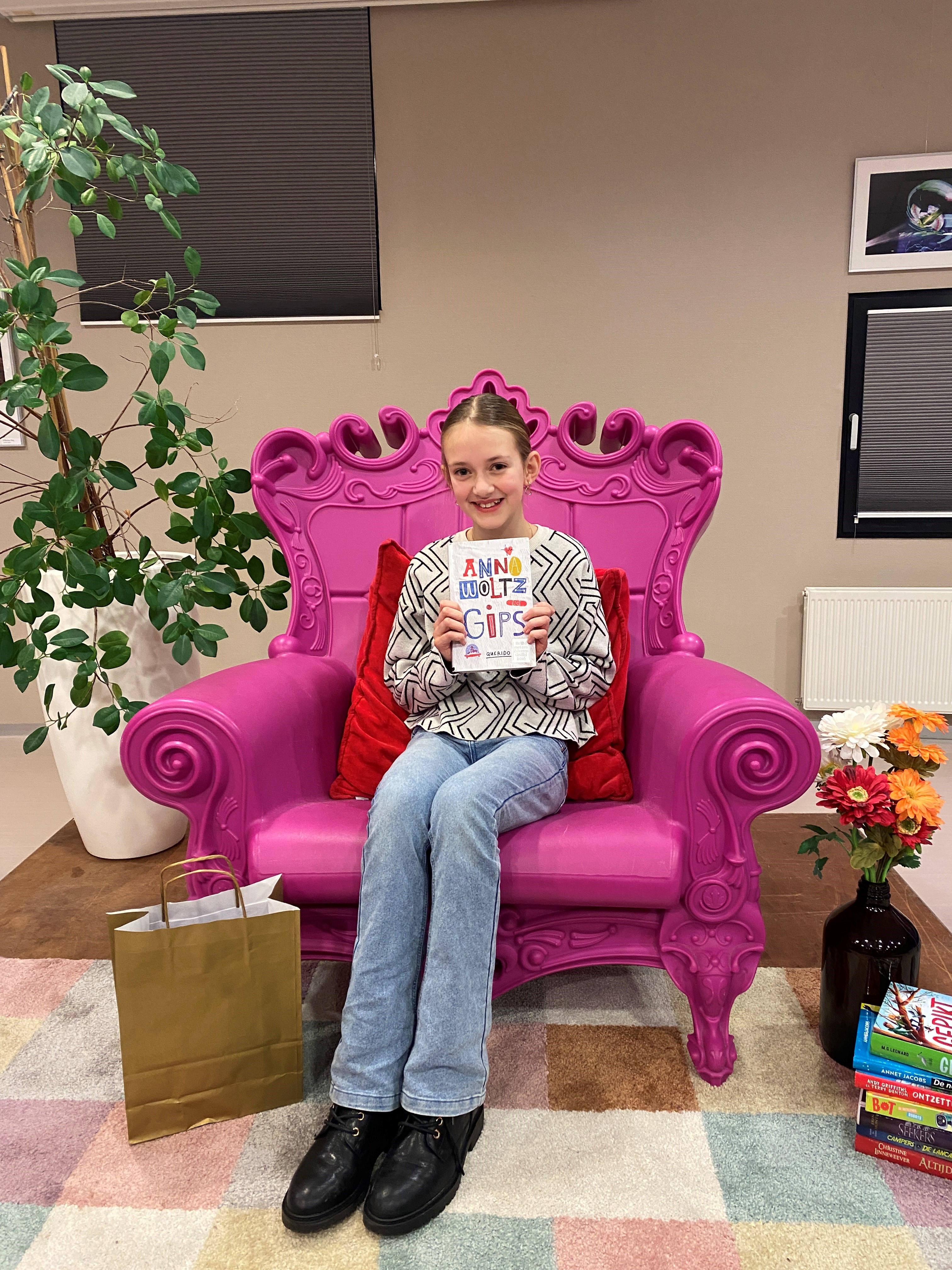 Noémi Seinen zit op een grote, roze stoel met een boek in haar handen