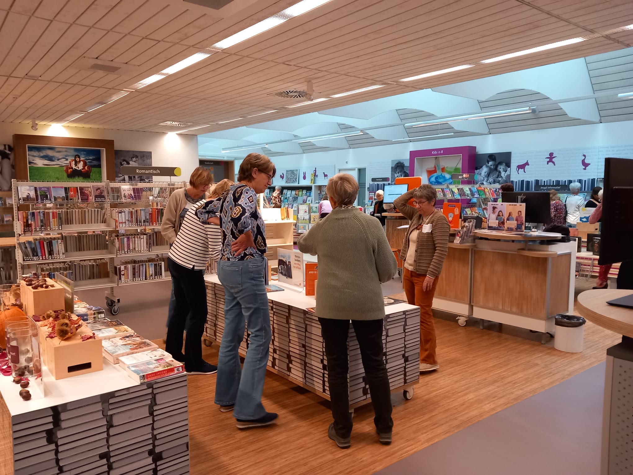 Een klein groepje vrijwilligers zijn in gesprek rondom een thematafel.