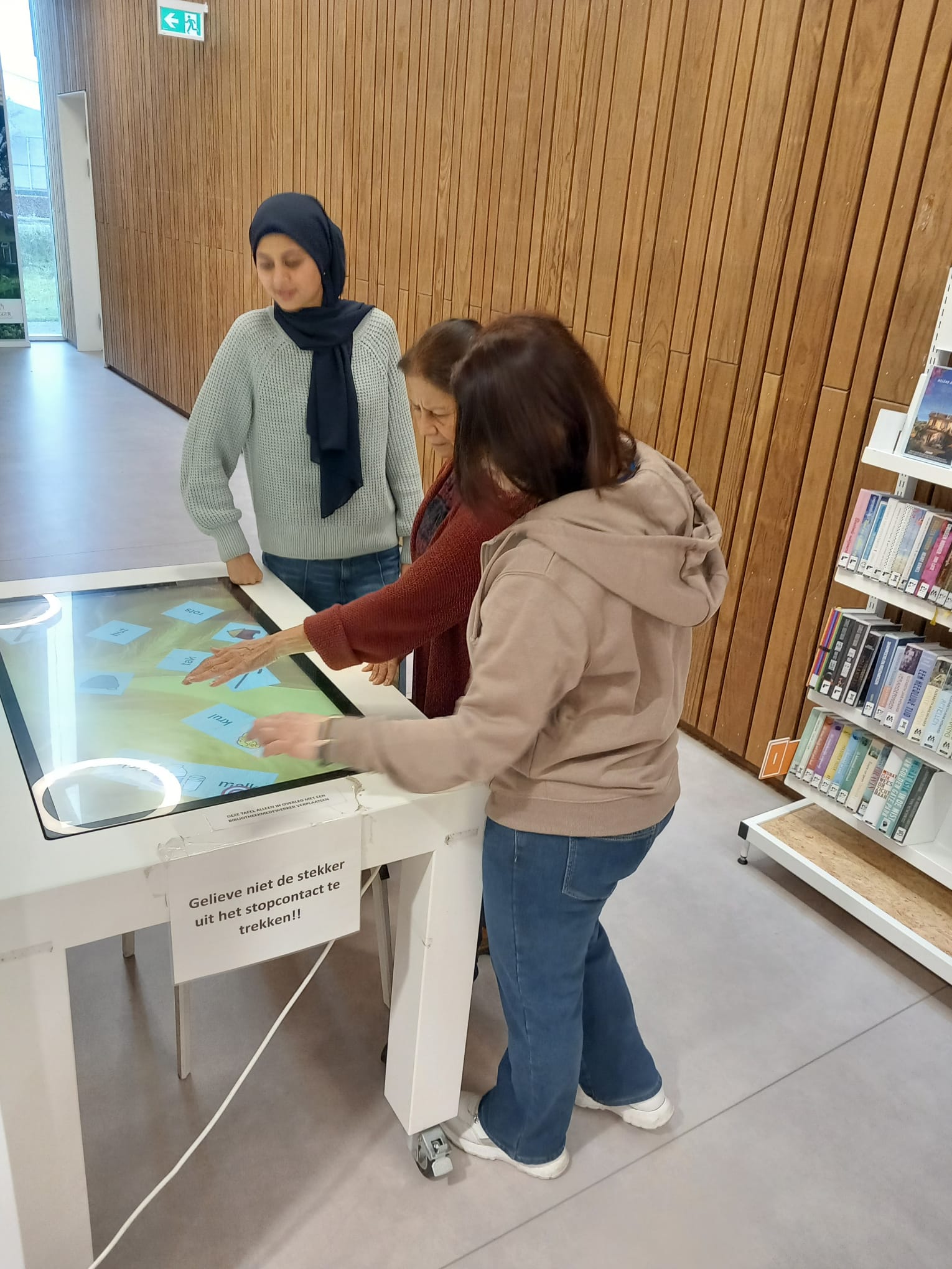 3 deelnemers oefenen op een multitouchtable met taalspelletjes