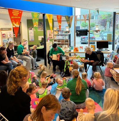 2 vrijwilligers lezen voor aan jonge kinderen en hun ouders en verzorgers in Bibliotheek Oudleusen
