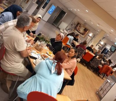 Twee tafels in de bibliotheek Lemelerveld waaraan mensen met elkaar in gesprek zijn. 