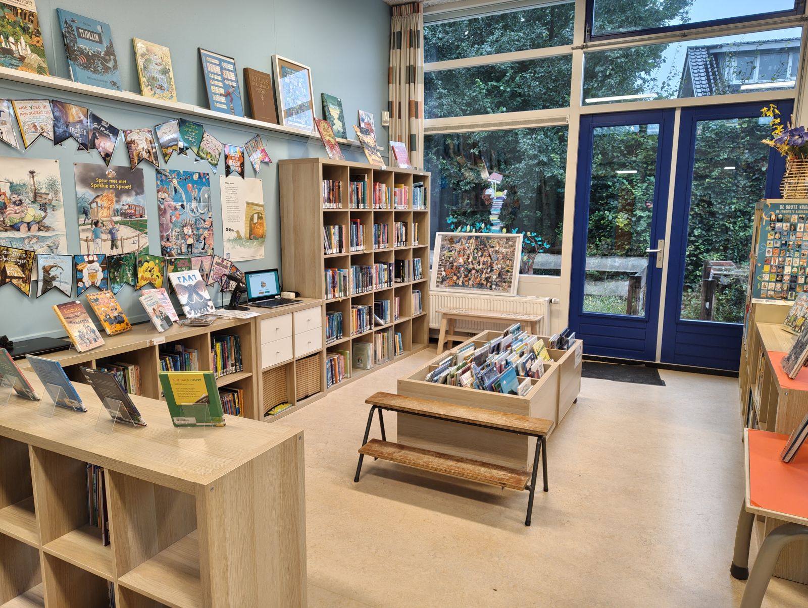 Kasten en bakken met boeken, fotolijsten met posters en vlaggetjes allemaal te maken met jeugdliteratuur. 