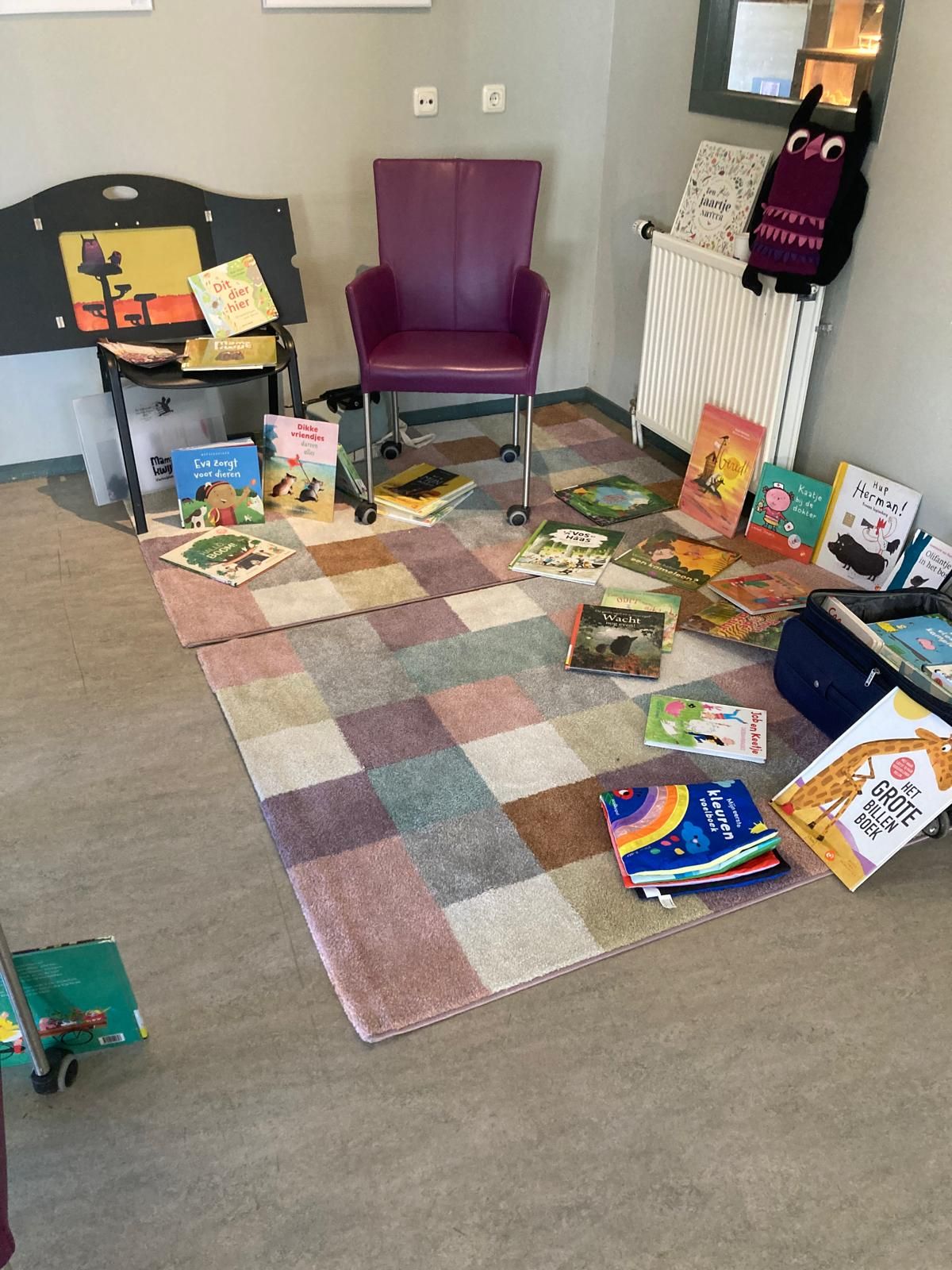 Stoel met daaromheen allerlei prentenboeken op een groot, geblokt kleed