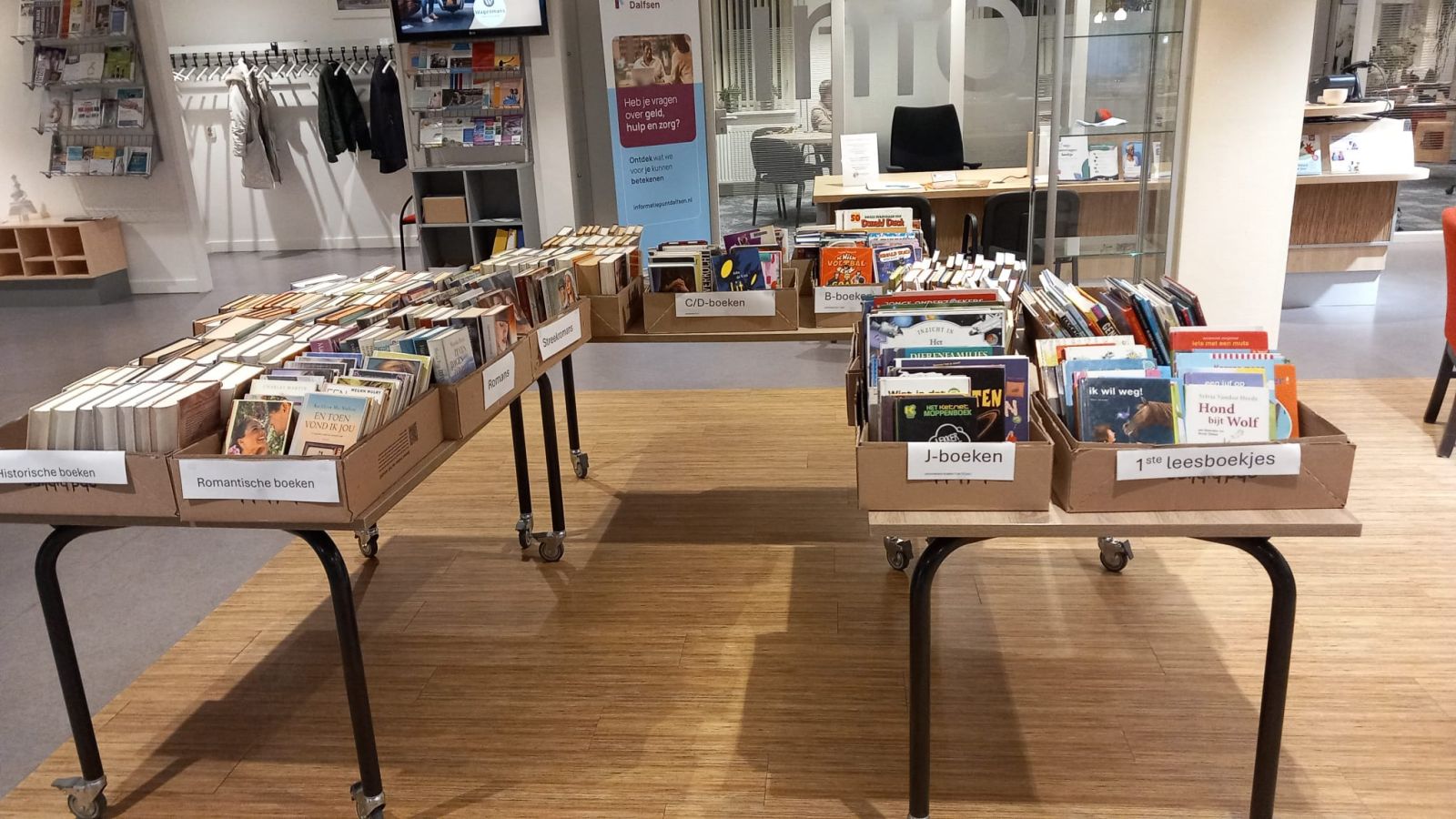 Tafel met dozen waarin boeken zitten van verschillende genres die te koop zijn. 