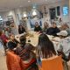 Groep mensen zit aan een tafel en is in gesprek met elkaar. 