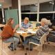 3 mensen overleggen aan een tafel vol met papier en 3 kopjes koffie.