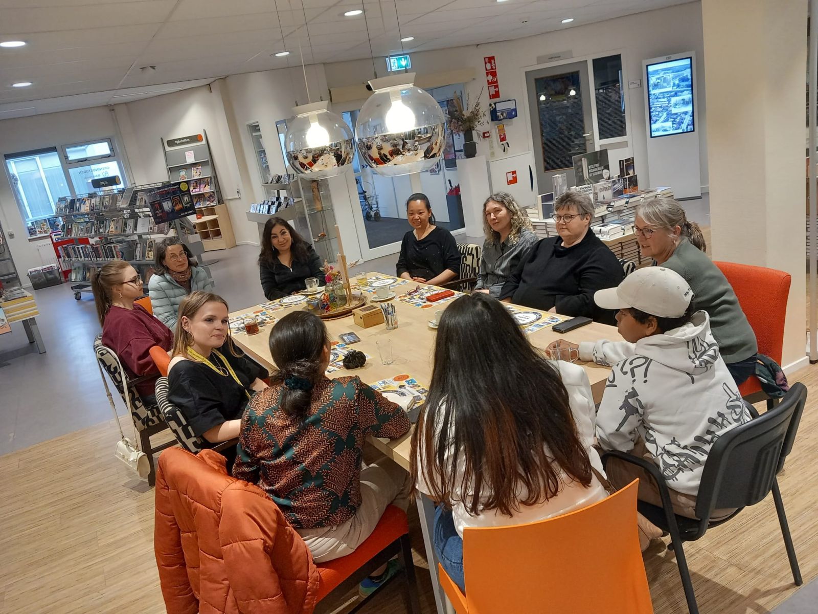 Groep mensen zit aan een tafel en is in gesprek met elkaar. 